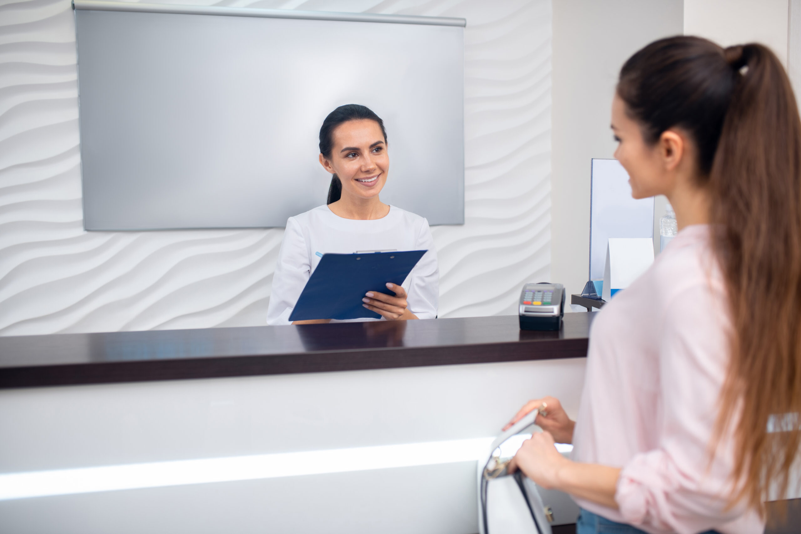Female patient consulting with a receptionist about neurotoxin procedures.